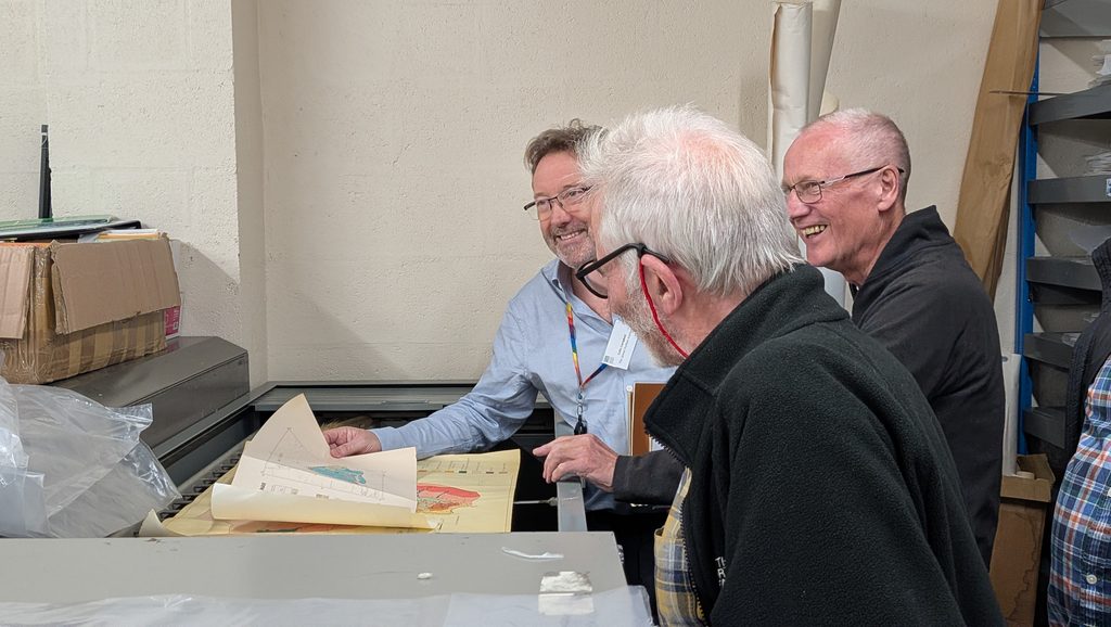 A group of former soil surveyors looking through historic soil maps and archive materials during a visit to the Craigiebuckler campus.